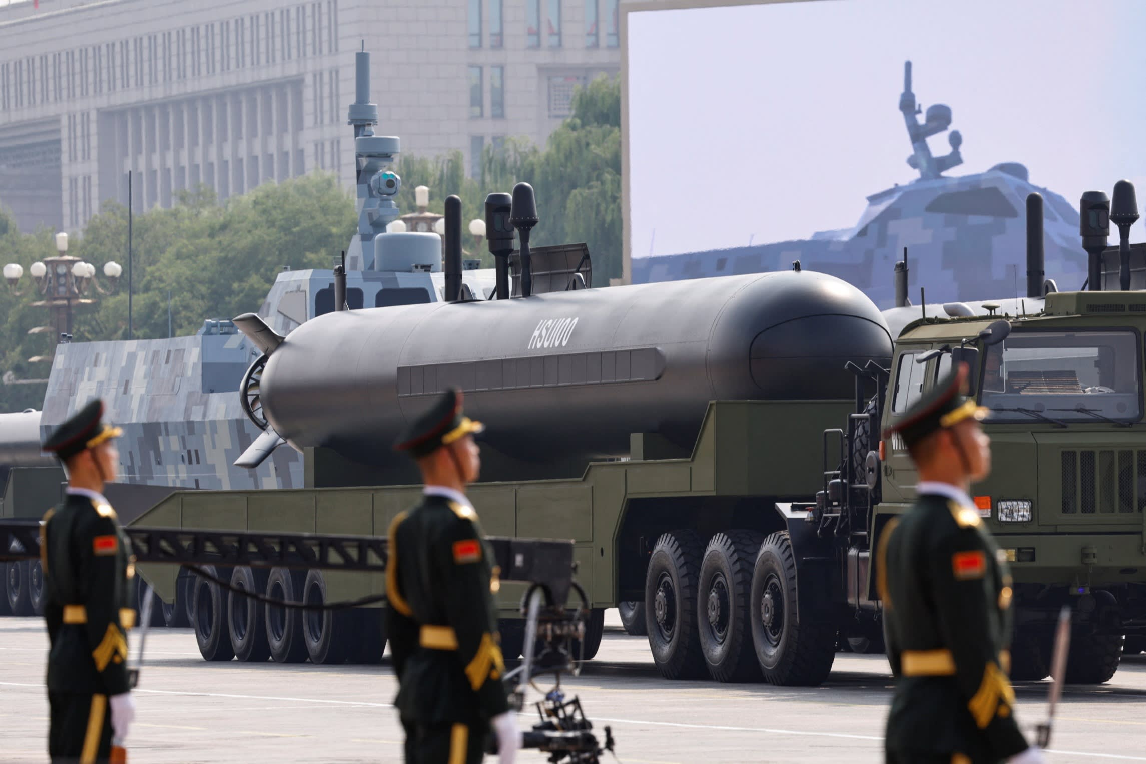 Members of the People's Liberation Army stand in front of an HSU100 unmanned underwater vehicle displayed on a military truck during a parade.