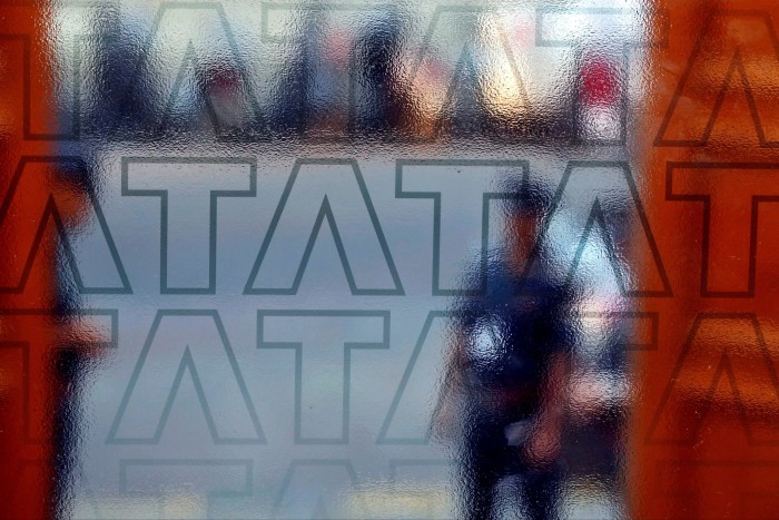 A security guard is seen through frosted glass with the Tata logo at the TCS headquarters exit gate
