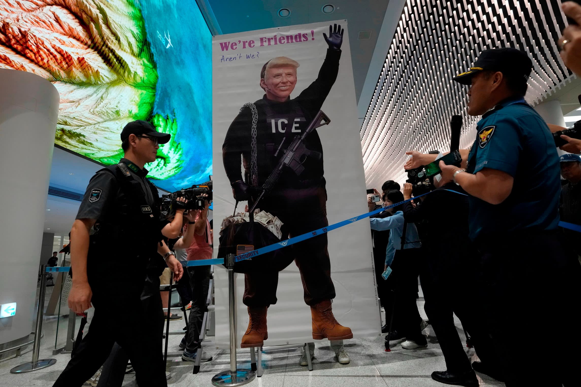 A banner showing a satirical image of U.S. President Donald Trump in tactical gear with police and media nearby at Incheon International Airport.