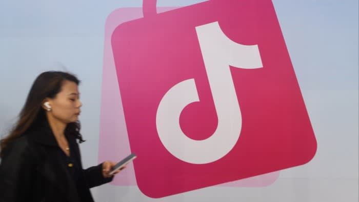 A woman walks past a TikTok logo