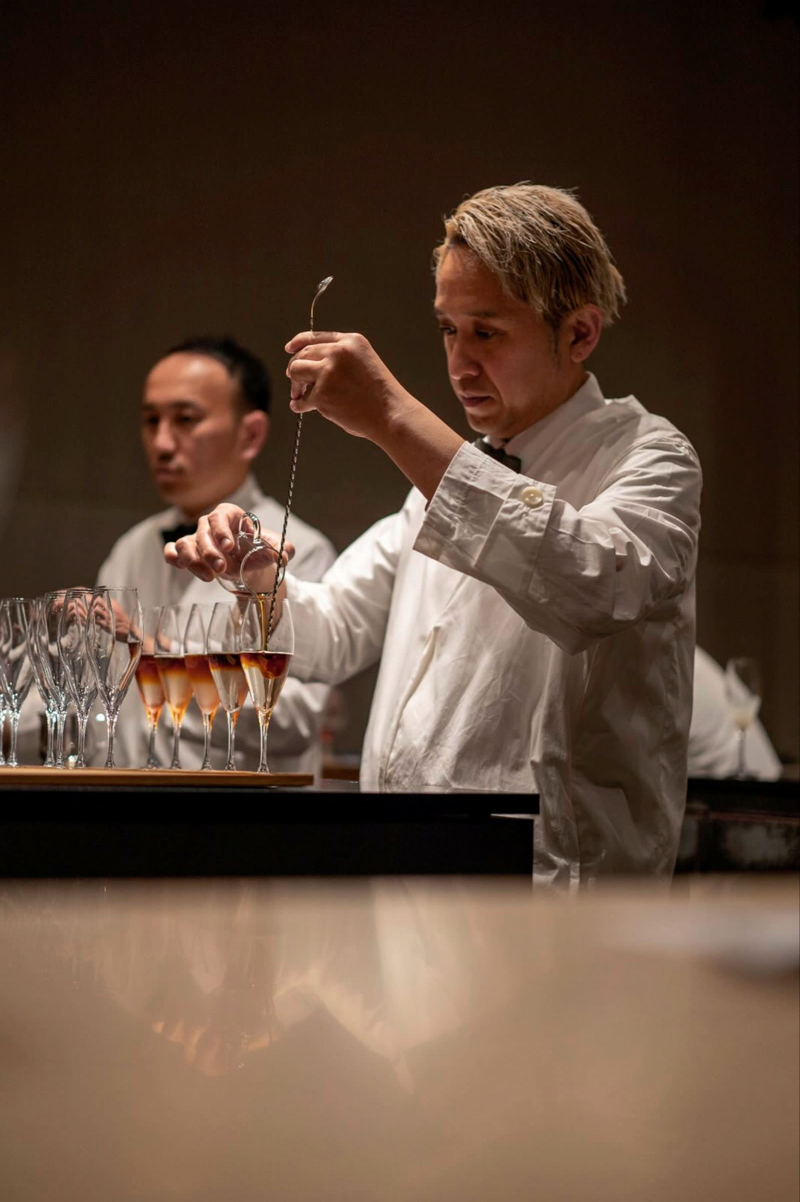 Koffee Mameya Kakeru’s head bartender Akira Zushi making a cascara and cold-brew mocktail, with another staff member nearby.