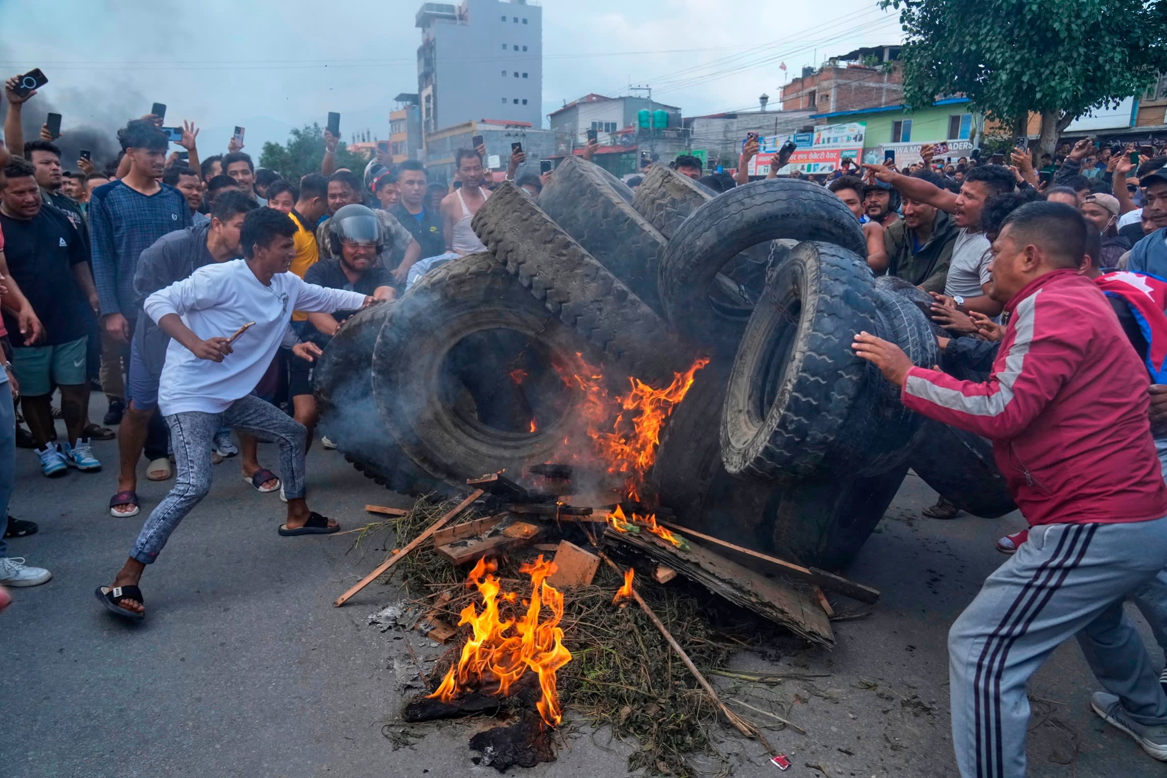Protesters putting tyres on a fire set on a Kathmandu street