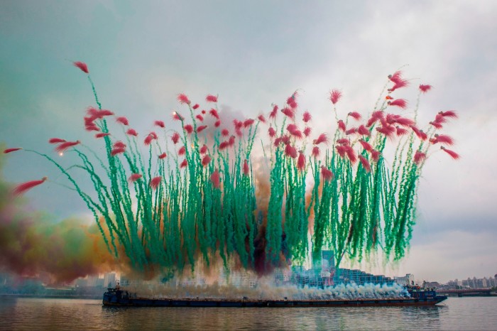 A series of spectacular pyrotechnic explosions on a riverfront have been staged to look like a giant bunch of flowers, with green stems of smoke and red flower explosions. 
