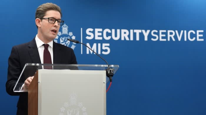 Sir Ken McCallum speaks at a podium in front of a blue backdrop with the MI5 Security Service logo.