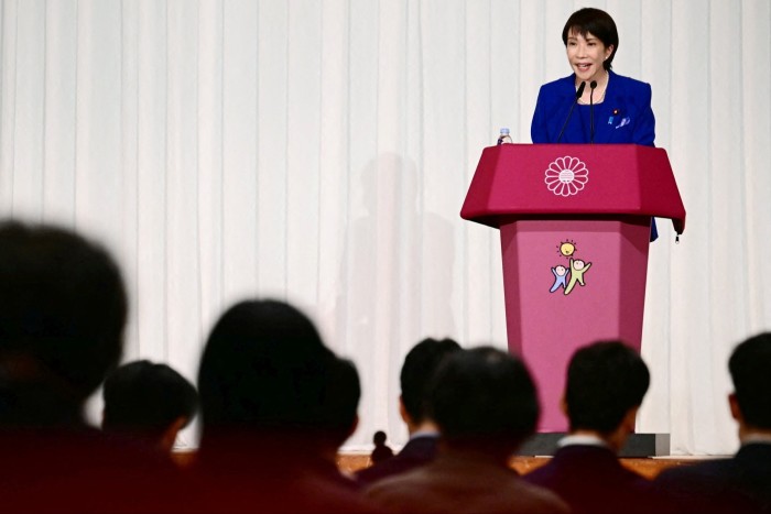 Sanae Takaichi speaks at a podium during a press conference after winning Japan’s ruling party leadership, facing an audience