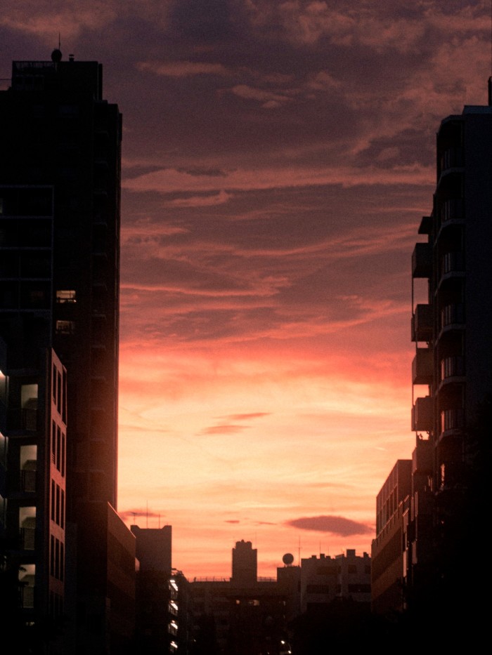 Sunset sky with vivid orange and purple hues above silhouetted buildings near Sendagaya Tunnel.