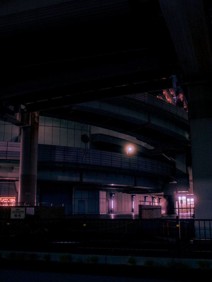 Detail of Tokyo’s Sunshine City shopping mall at night, with multiple layers of elevated walkways and columns, as well as purple and pink lighting accents.