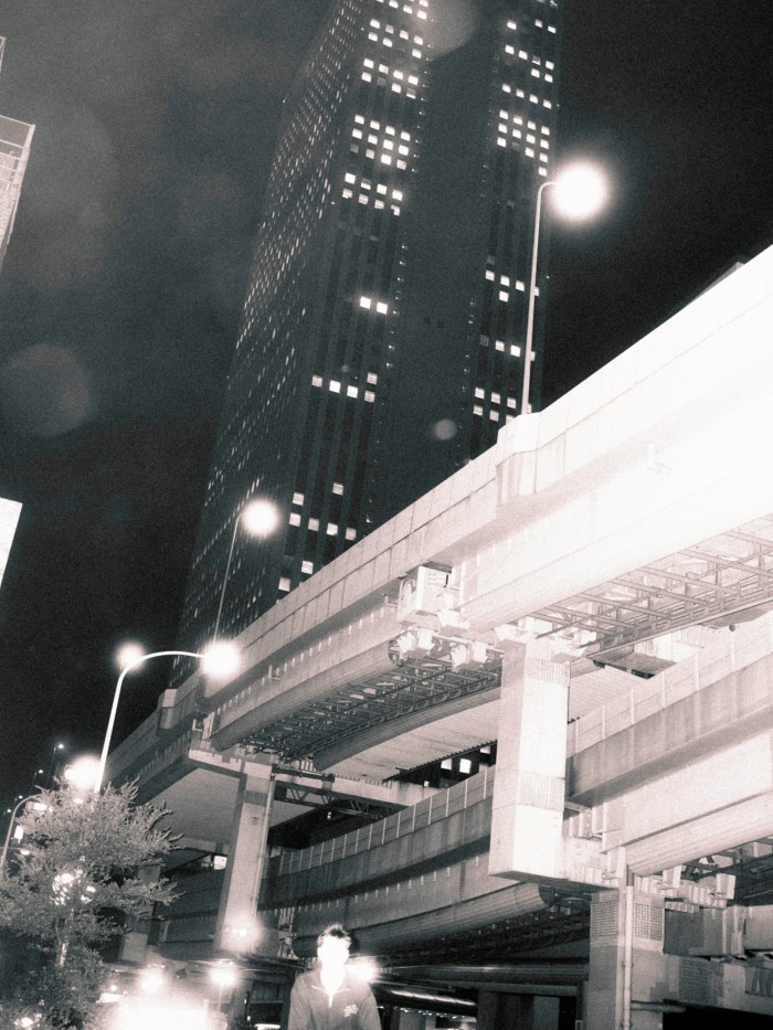 Towering highways crisscross in front of Sunshine City at night, with lights illuminating the scene.