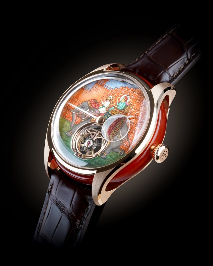 A luxury wristwatch with a painted dial showing an elephant carrying two riders against an ornate palace backdrop.