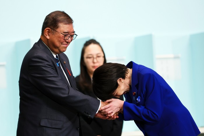 Newly elected leader of Japan’s Liberal Democratic party Sanae Takaichi bows as she shakes hands with outgoing Prime Minister Shigeru Ishiba in Tokyo on Saturday