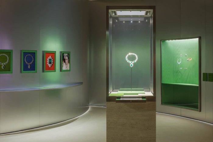 An emerald necklace on display in a glass vitrine in a large exhibition space.