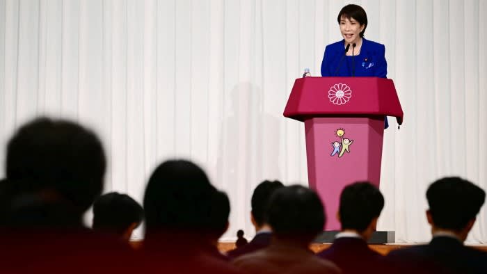 Sanae Takaichi speaks at a podium during a press conference after winning Japan's ruling party leadership, facing an audience
