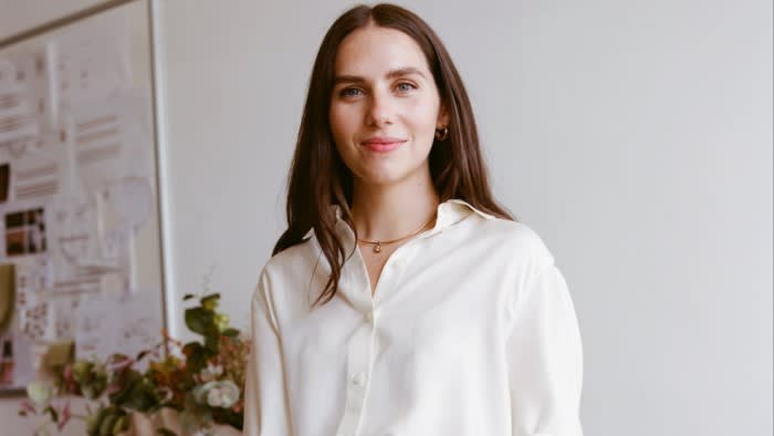 A woman in a white shirt and pants standing in a boutique or design studio