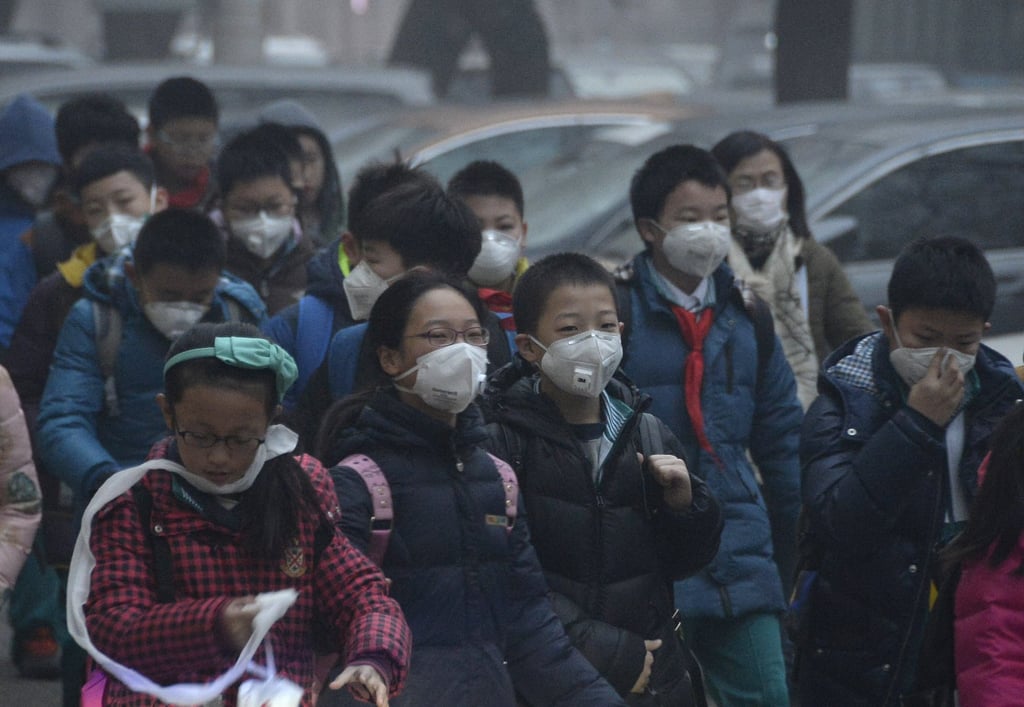 Students wearing masks walk down a smog-shrouded street in Beijing in 2015. Photo: Xinhua