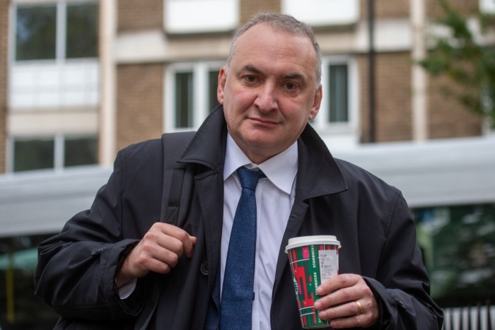 Chris Wormald holds a coffee cup and carries a backpack.