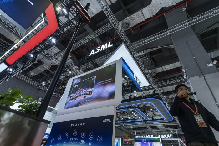 Signage for ASML Holding NV displayed above a booth at the China International Import Expo, with a person standing nearby.