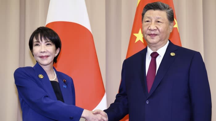 Xi Jinping shakes hands with Sanae Takaichi, with Japanese and Chinese flags behind them