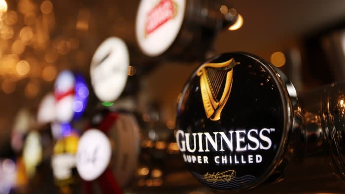 A close-up of a Guinness beer tap handle in a London pub, with other tap handles blurred in the background.