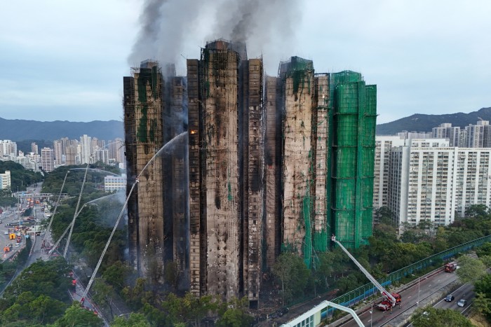 Flames and thick smoke rise from the Wang Fuk Court housing estate as firefighters use hoses to battle a major fire.