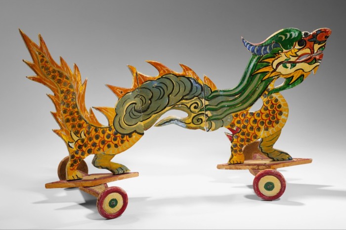 A painted wooden toy in the shape of a dragon, its feet on wheels