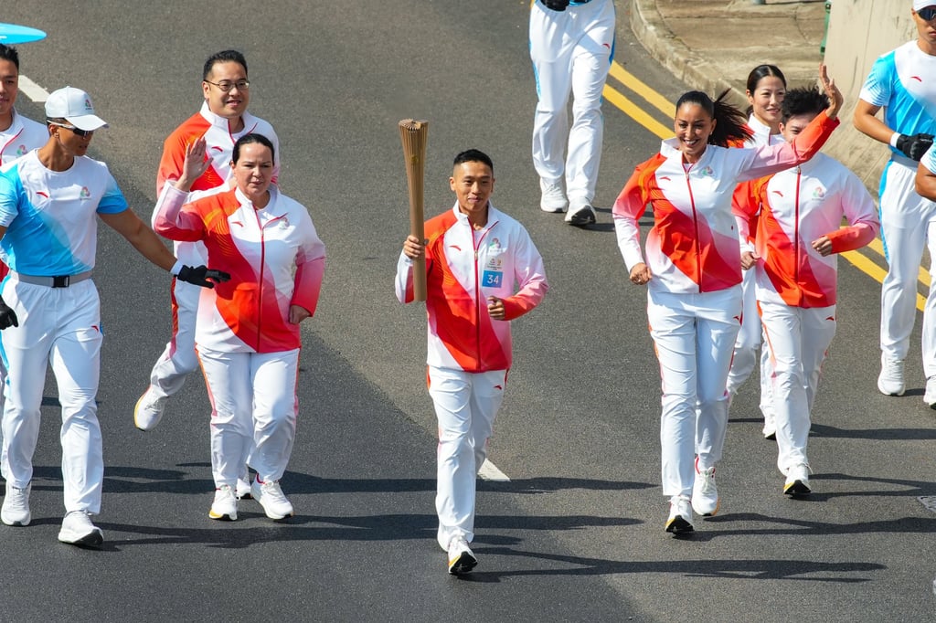 Renowned horse racing jockey Vincent Ho Chak-yiu carries the torch on Salisbury Road during the 15th National Games torch relay in Hong Kong, on November 2. Photo: Sun Yeung