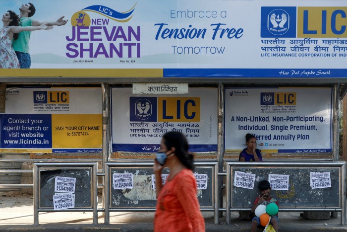 A woman walks past a bus stop in Mumbai that has a Life Insurance Corporation of India advertisement