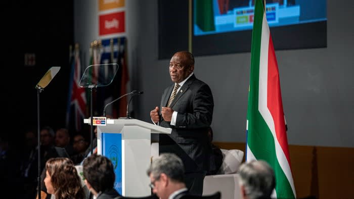 South African President Cyril Ramaphosa speaks at a podium during the G20 finance meetings, with a South African flag beside him.