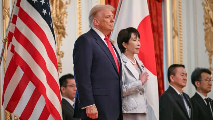 Takaichi and Trump standing together flanked by their national flags.
