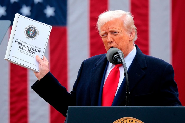 Donald Trump holds up a copy of the 2025 National Trade Estimate Report on Foreign Trade Barriers while speaking at a podium.