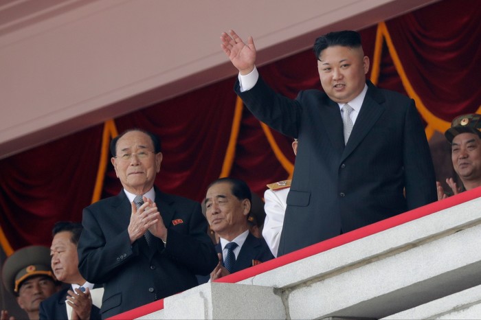 Kim Jong Un waves as Kim Yong Nam, Choe Ryong Hae, and Pak Pong Ju clap during a military parade in Pyongyang.