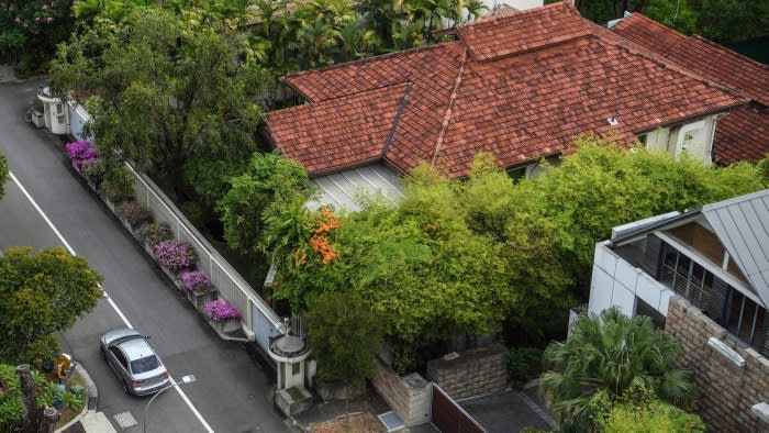 The house at 38 Oxley Road with a red-tiled roof, surrounded by lush greenery and a white boundary wall along the street.