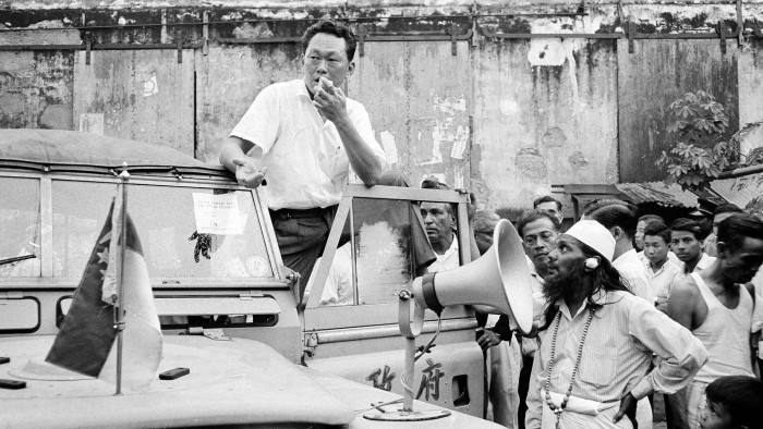 Singapore Prime Minister Lee Kuan Yew stands on the running board of a government vehicle in Singapore as he addresses the crowd in a slum area, July 29, 1964. Lee, popular on the island, asked for a halt in the racial strife that has struck the island city. (AP Photo)