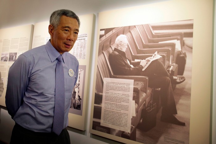 Lee Hsien Loong stands near a large photograph of his father, Lee Kuan Yew, at a remembrance ceremony.