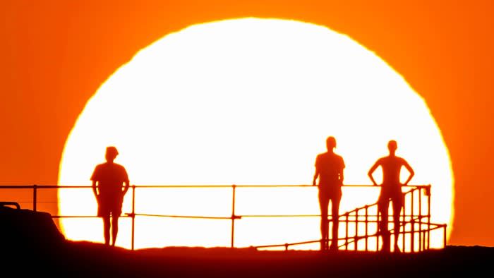 People watch as the sun rises over Ben Buckler Point in Bondi, Sydney, Australia