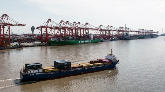 Gantry cranes line the dock as container ships, including a large green vessel labeled "EVERGREEN," are loaded at Yangshan Deepwater Port in Shanghai.