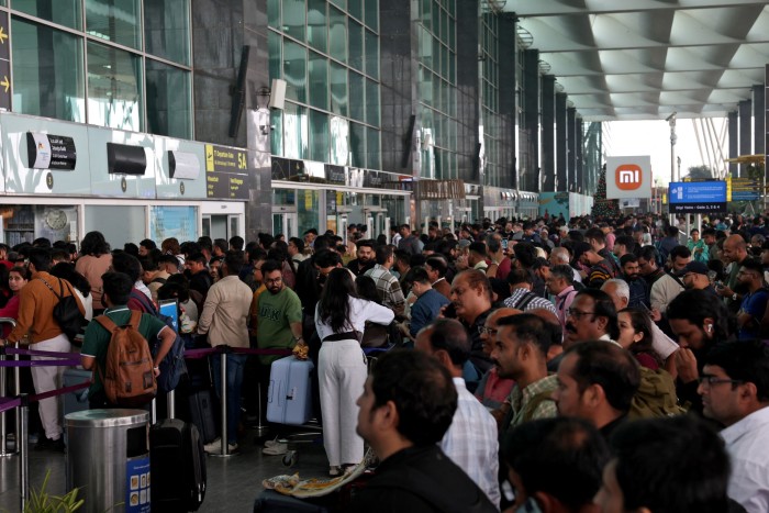 Large crowds of travellers wait in long queues at IndiGo ticketing kiosks inside Kempegowda International Airport
