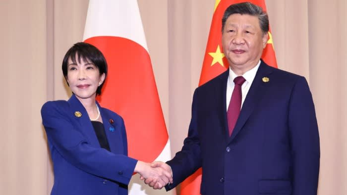 Sanae Takaichi shakes hands with Xi Jinping in front of Japanese and Chinese flags at the Japan-China summit.