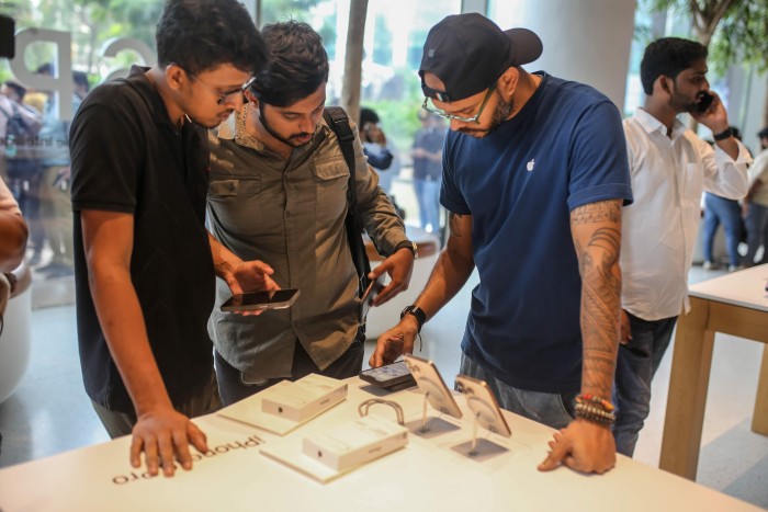 A shop assistant serves a customer inside the Apple Inc store in Mumbai.