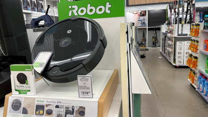 Roomba 694 robot vacuum displayed on a shelf in a Bed Bath and Beyond store with iRobot branding and a price tag.