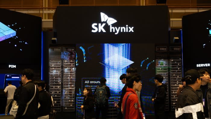 Visitors walk and stand in front of the SK Hynix booth featuring large digital displays and server racks at the SEDEX exhibition.