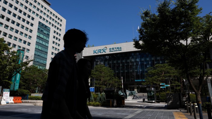 The Korea Exchange building in Seoul with two people in silhouette walking in the foreground.