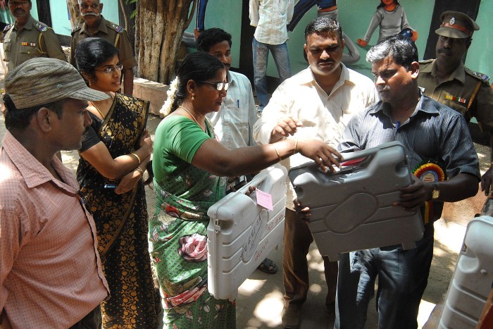 Indian election officials deliver electronic voting machines at a polling station in Chennai
