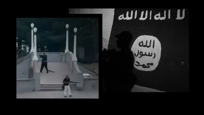 Two people dressed in black with guns; next to a mural with the Isis logo and a shadowed figure.