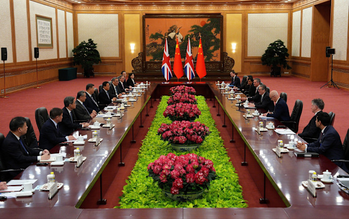 Keir Starmer and Xi Jinping sit at the head of a long table with UK and Chinese delegations during a formal meeting in Beijing.