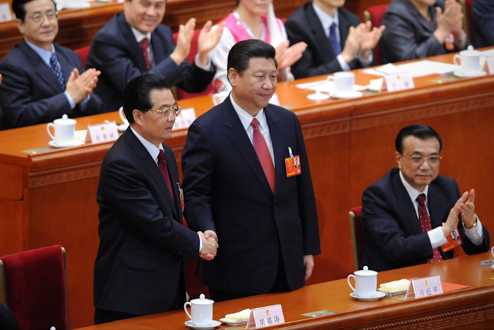 Hu and Xi shaking hands during the Chinese National People’s Congress in 2013, as other delegates applaud