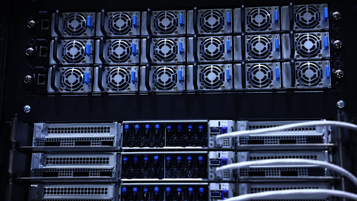 Nvidia GB200 NVL72 GPU server rack with multiple cooling fans and server units, connected with white cables for AI computing.