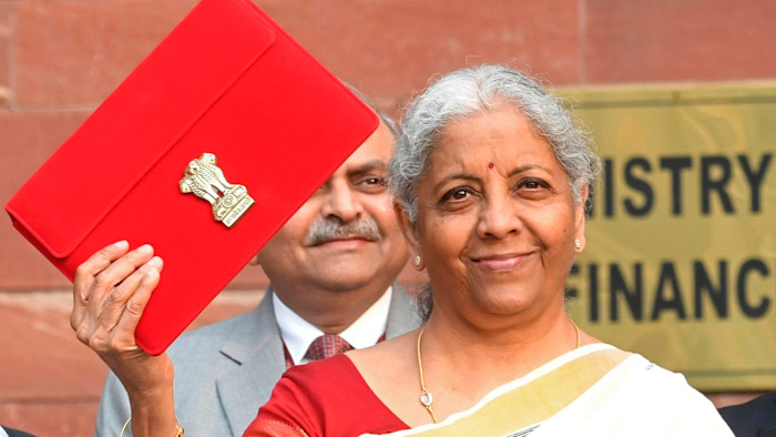 Nirmala Sitharaman holds up a red pouch with the Indian national emblem, smiling before presenting the federal budget.