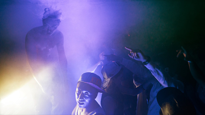 Audience members raise their hands toward a performer on a dimly lit stage