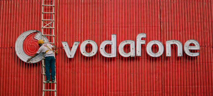 A worker replaces fluorescent lights on a Vodafone billboard 