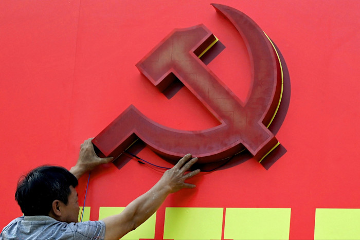 A worker installs a large hammer and sickle emblem on a red billboard for the 14th Congress of the Vietnamese Communist Party